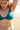 Haut de bikini vert émeraude en seaqual porté par une jeune femme à la plage.
