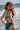 Jeune femme en bikini ecoresponsable de couleur verte se tient face à la mer.