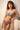Jeune femme de face accoudée porte un ensemble bleu myosotis en dentelle recyclée de la marque de lingerie éco-responsable Olly.