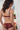 Une jeune femme porte un ensemble de lingerie bordeaux en dentelle recyclée.