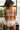 Jeune femme brune les cheveux attachés, de dos, qui porte un ensemble de lingerie blanche.