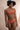 Une jeune femme porte de la lingerie en dentelle recyclée et coton bio de couleur terracotta.