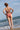 Jeune femme en bikini terracotta de la marque durable Olly se tient debout face à la mer.