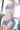 Jeune femme debout à contre-jour, en ensemble de lingerie bleue en coton biologique de la marque de lingerie Olly.