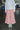 Close up shot of a woman wearing Saywood's Amelia Wide Leg Culotte Trousers in pink cotton corduroy, ankle shy length, with mint green cowboy boots and the Lela Boxy Patch Pocket Shirt in white recycled cotton.