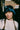 Close up of a woman standing in dappled light, with plaited pigtails. She wears Saywood's Japanese denim Reversible Bucket Hat and white recycled cotton gathered neck Marie Blouse. The gathered detail around the neck of the blouse can be seen in the image.