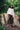 Model stands, legs in wide stance, in front of tree stumps and greenery. She wears Saywood's white Marie A-line Blouse with a red check neckerchief tied round her neck. Worn with Saywood's Amelia wide leg trouser in khaki and black and white zebra print sandals.