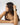 profile of a woman's face with her hand running through her hair, on her wrist is an apple with with a white leather band #color_white