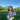 Woman standing outdoors in a blue mohair cardigan with green grass and trees.