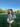 Woman standing outdoors in a blue mohair cardigan with green grass and trees.