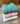 Stack of three folded Mohair pointelle knit vests in green, pink, and white on a wooden surface
