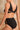 Jeune femme de dos porte un ensemble de lingerie noir en coton biologique et tulle recyclé de la marque de lingerie éthique et durable Olly.