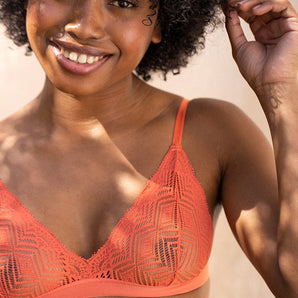 Une jeune femme portant un soutien-gorge terracotta sourit à la caméra.