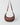 A reddish brown crescent-shaped crossbody convertible crescent bag made of a vintage nappa, featuring a matching adjustable shoulder strap with gold-tone hardware, set against a light gray studio background.#color_bordeaux-vintage