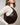 A woman wearing a cream ribbed turtleneck sweater carries a HYER GOODS Piccola ring bag dark brown snakeskin-patterned crescent shoulder bag with a gold-tone clasp against a plain light gray background. #color_brown-python-embossed