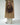 a cropped photo of a woman in cream pants, a khaki trench and a brown suede crescent bag hanging from her fingertips #color_chocolate-suede