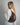 a blond woman wearing an oversized white shirt stands with her back to the camera, wearing a burgundy shoulder bag with gold ring hardware #color_bordeaux-vintage