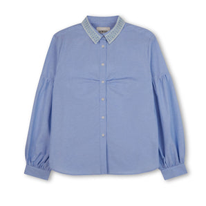 Womens pale blue shirt with lace trim collar and volume sleeves. Soft gathering is at the bust, with shirt made in recycled cotton. Shirt is on a white background