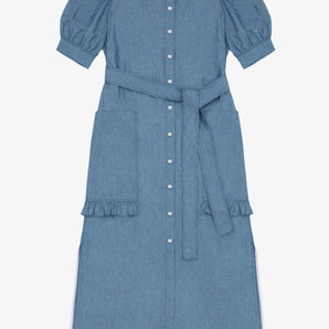 Womens denim puff sleeve dress in light wash Japanese denim, long line with side splits at the hem. Dress has patch pockets at the hip with ruffles at the bottom of the pockets, with a tied matching belt around the waist. Dress is on a white background.