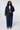 Woman wearing a navy blue blazer, white top, and wide-leg jeans, posing against a white background.