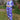 Woman wearing a blue and light blue patterned outfit standing in a garden.