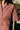Close up of the Frances Unisex Cuban Shirt in red and white stripe. A woman is wearing the short sleeve shirt and the crop of the image shows the Saywood signature embroidered flower on the right chest pocket. Grass and a wooden fence can be seen behind her.