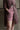 Close up of the lower body of a woman. She is wearing Saywood's Bessie A-line Shorts in berry red stripe, with the Etta Oversized Shirtdress in micro red check, half unbuttoned from the waist down. The woman has her hand in her shorts pocket.