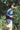 A woman is running through green nature, wearing the Etta Oversized Japanese Denim Shirtdress, worn over tan trousers.