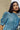 Close up of a woman wearing Saywood's Rosa denim shirtdress in light wash Japanese denim; a long line style with patch pockets and ruffles, a belt tied round the waist. The gathered puff sleeve can be see as a focal point in the shot.